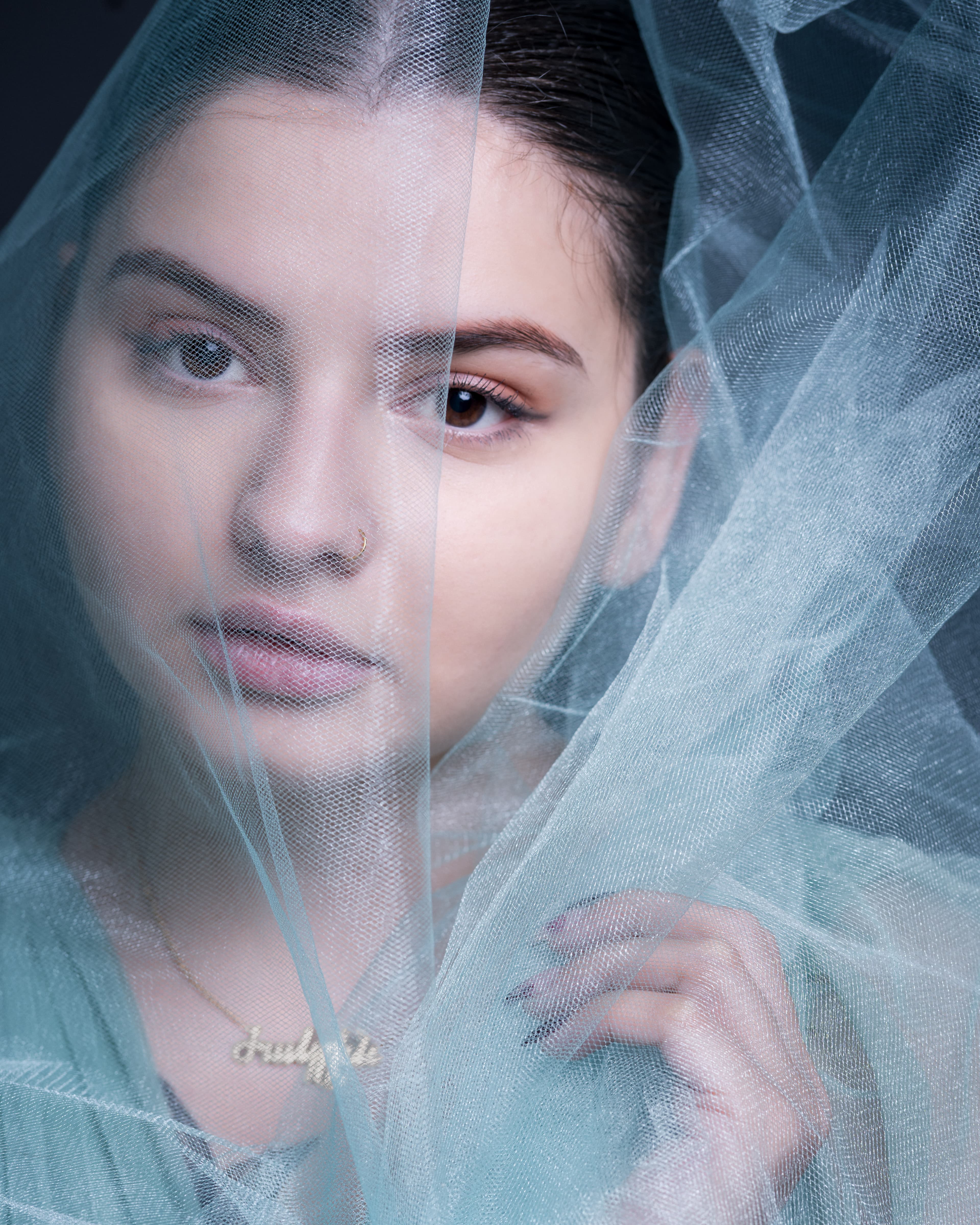 Close-up Portrait einer Frau hinter transparentem Tüll, ruhiger Blick